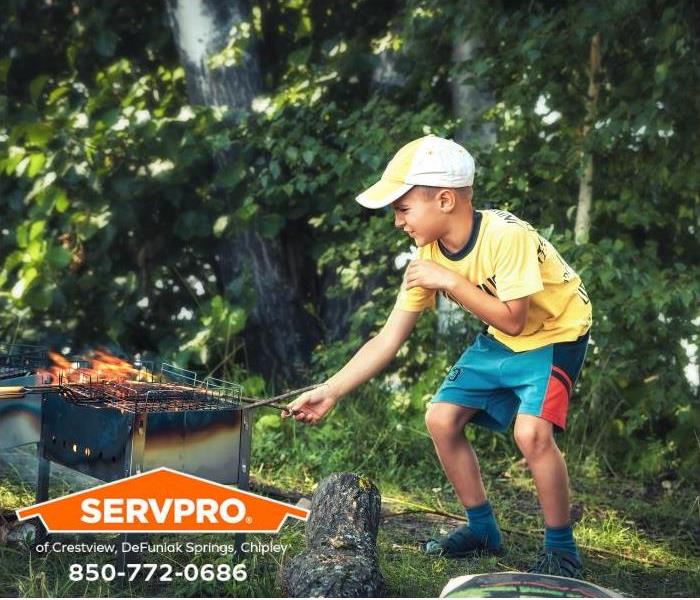 A mischievous boy is playing with fire on an outdoor grill.