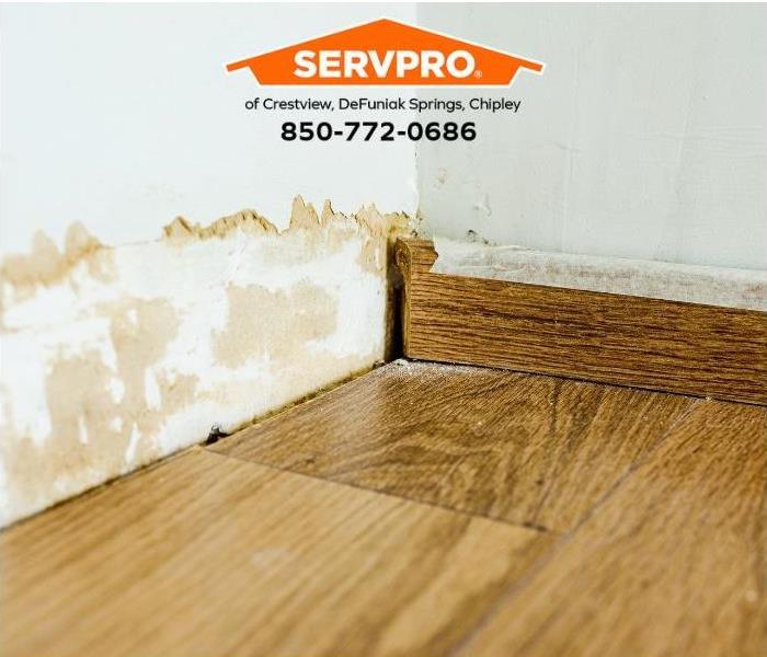 A baseboard is removed, exposing water damage in a home.