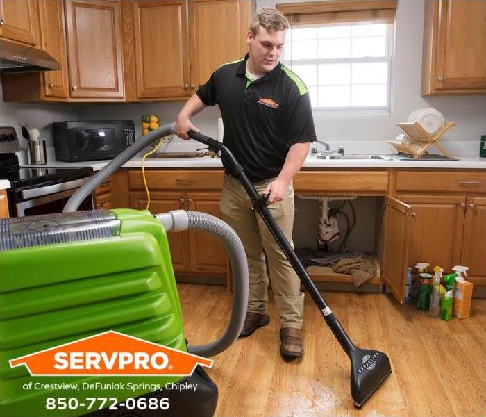 A SERVPRO water restoration technician is extracting water from a kitchen floor.