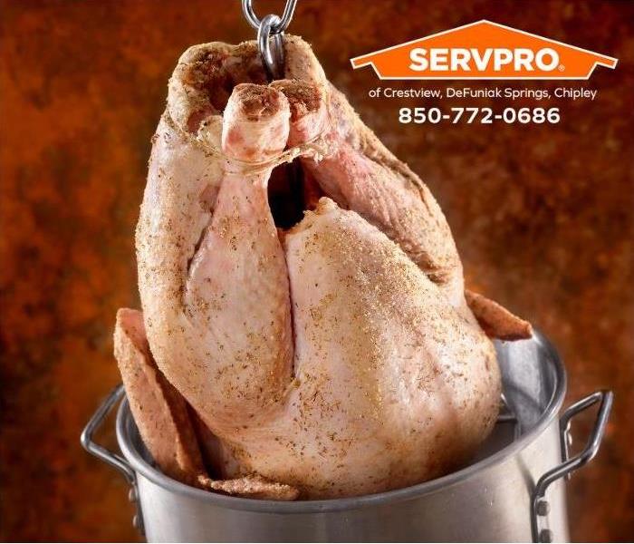 A turkey is being lowered into a turkey fryer filled with too much oil.