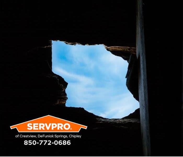 Clouds and blue sky are visible through a hole in a roof.